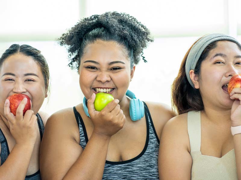 Drei &Uuml;bergewichtige beissen in einen Apfel